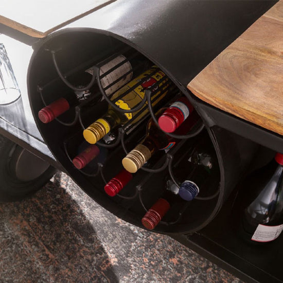 Industrial airplane-engine style bar cart with propeller decoration and dual shelves, featuring wooden tabletop, black metal frame, large rubberized wheels, hanging wine-glass rack and storage for bottles, set in a modern living-room environment