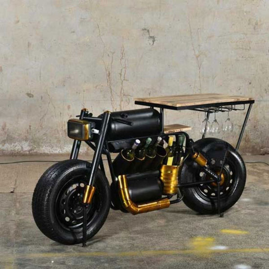 A bar table with a vintage motorcycle design, featuring a wooden tabletop, built-in wine rack, and glass holders. The table is styled with a black and gold finish and has a realistic motorcycle frame as a decorative element.