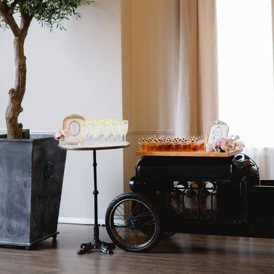 Decorative setup with a black carriage, table with cake, and decorative items in a room.