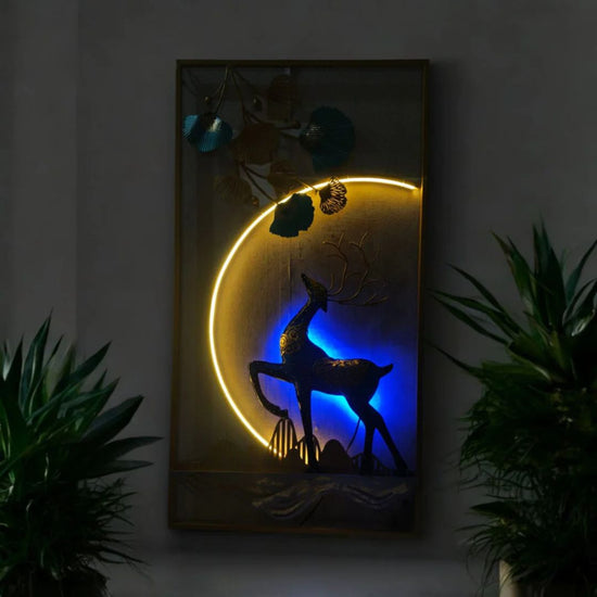 Decorative wall art with a deer silhouette on a moonlit background, illuminated by yellow and blue lights.