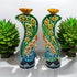 Decorative candle holders with peacock designs on a white background