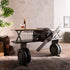 Industrial airplane-engine style bar cart with propeller decoration and dual shelves, featuring wooden tabletop, black metal frame, large rubberized wheels, hanging wine-glass rack and storage for bottles, set in a modern living-room environment