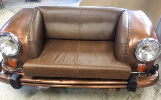Brown leather sofa designed to resemble a vintage car with headlights and bumper.