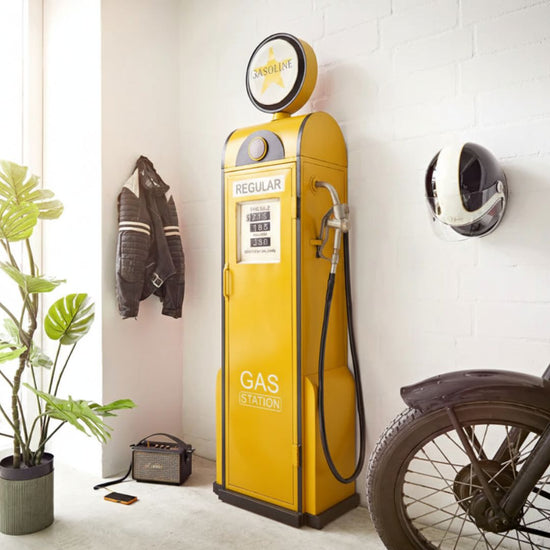 Yellow vintage-style gas pump in a modern indoor setting with a motorcycle and plant.