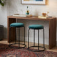 Two teal bar stools in front of a wooden bar with decorative items.