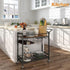 Kitchen island with a rolling cart holding kitchen items in a bright kitchen.