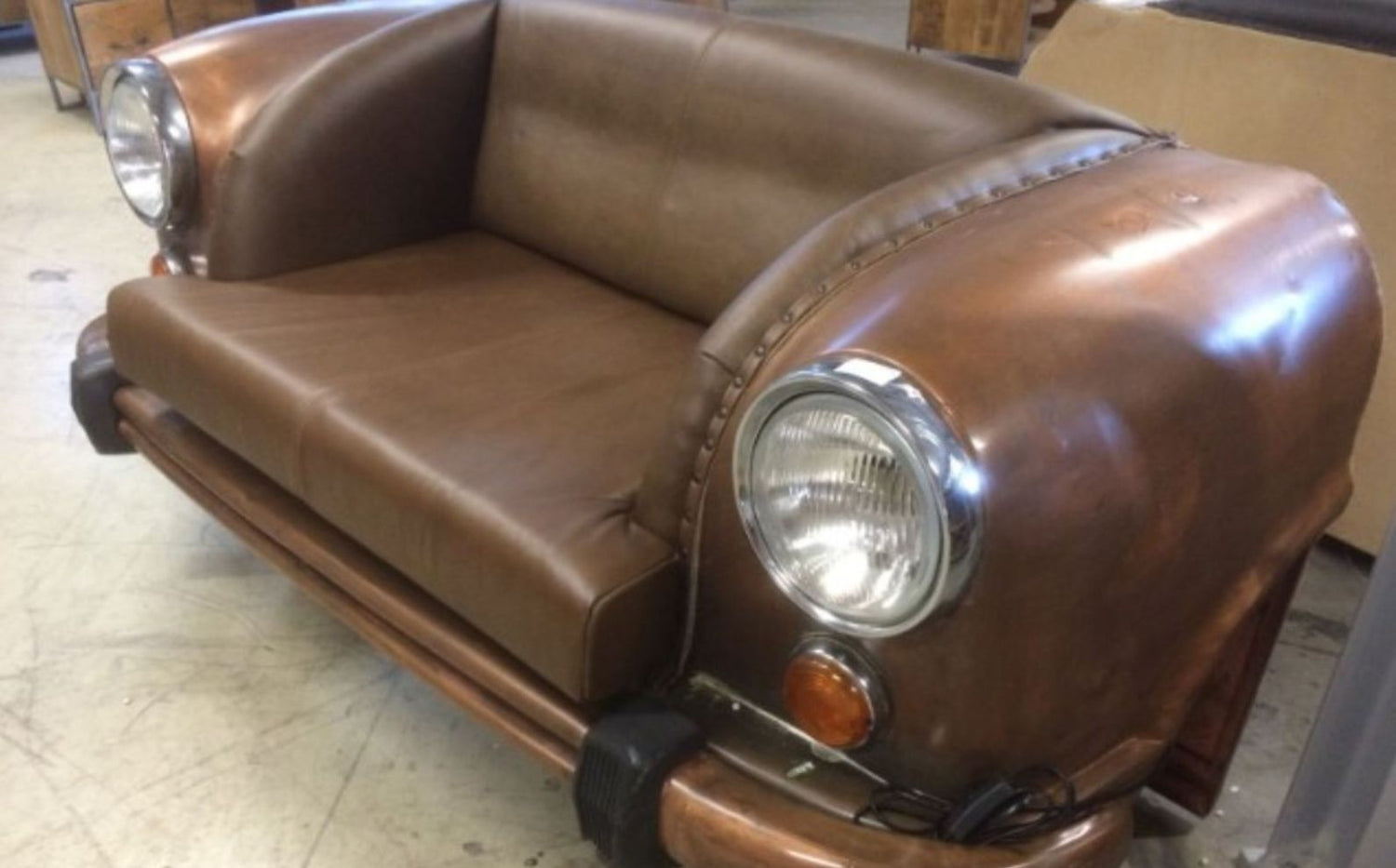 Brown leather sofa designed like a vintage car with headlights and bumper.