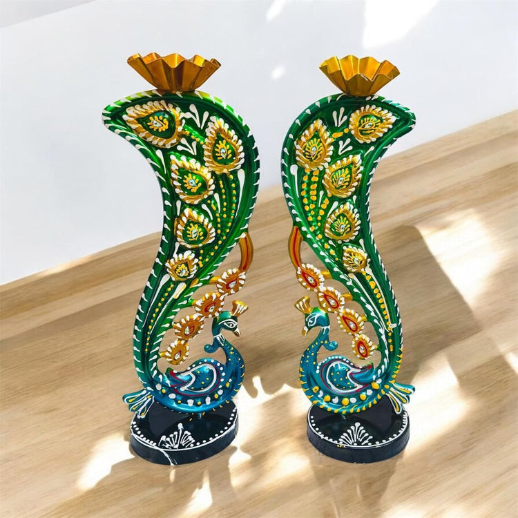 Decorative candle holders with peacock design on a wooden surface