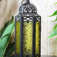 Vintage Moroccan Style Black Lantern with Yellow Glass Panels-Hansart-Hansart, Add a touch of exotic elegance to your home décor with this beautifully crafted Moroccan-style lantern. Featuring intricate cut-out patterns on a sturdy metal frame and vibrant yellow embossed glass panels, this lantern casts a warm, inviting glow when lit. Standing 11.5 inches tall, it’s perfect for tabletop centerpieces, hanging displays, or as a charming accent in both indoor and outdoor settings. Whether used with candles or 