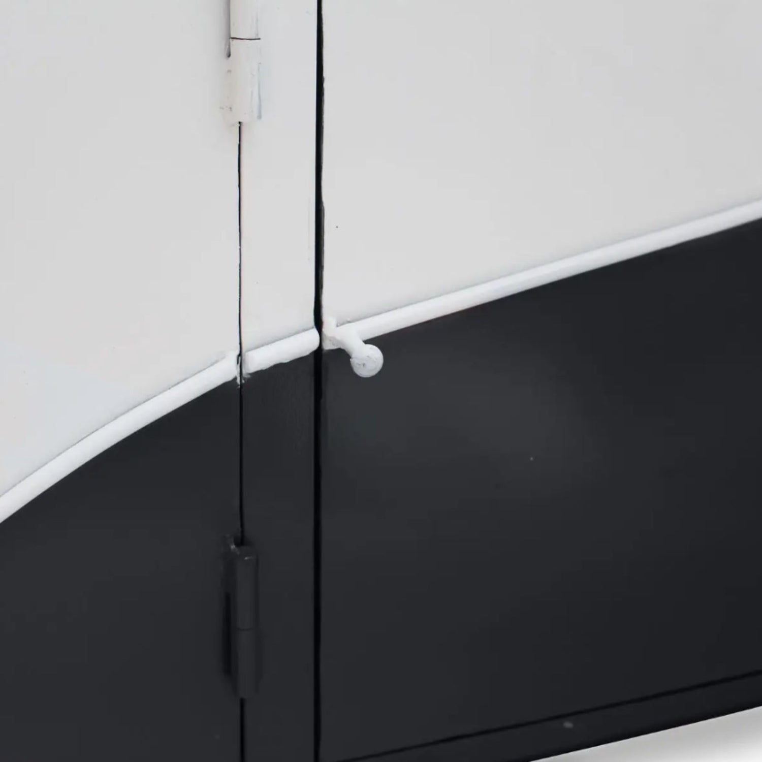 Close-up of a black and white door with a hinge