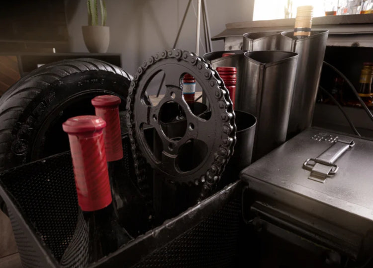 Bar cart with wine bottles, glasses, and cocktail shakers on a wooden floor.