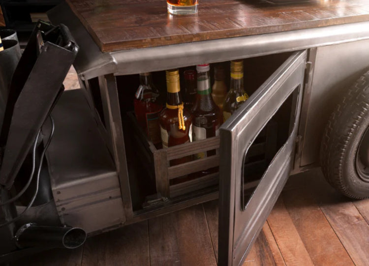 Bottles of alcohol in a wooden crate under an open cabinet door.
